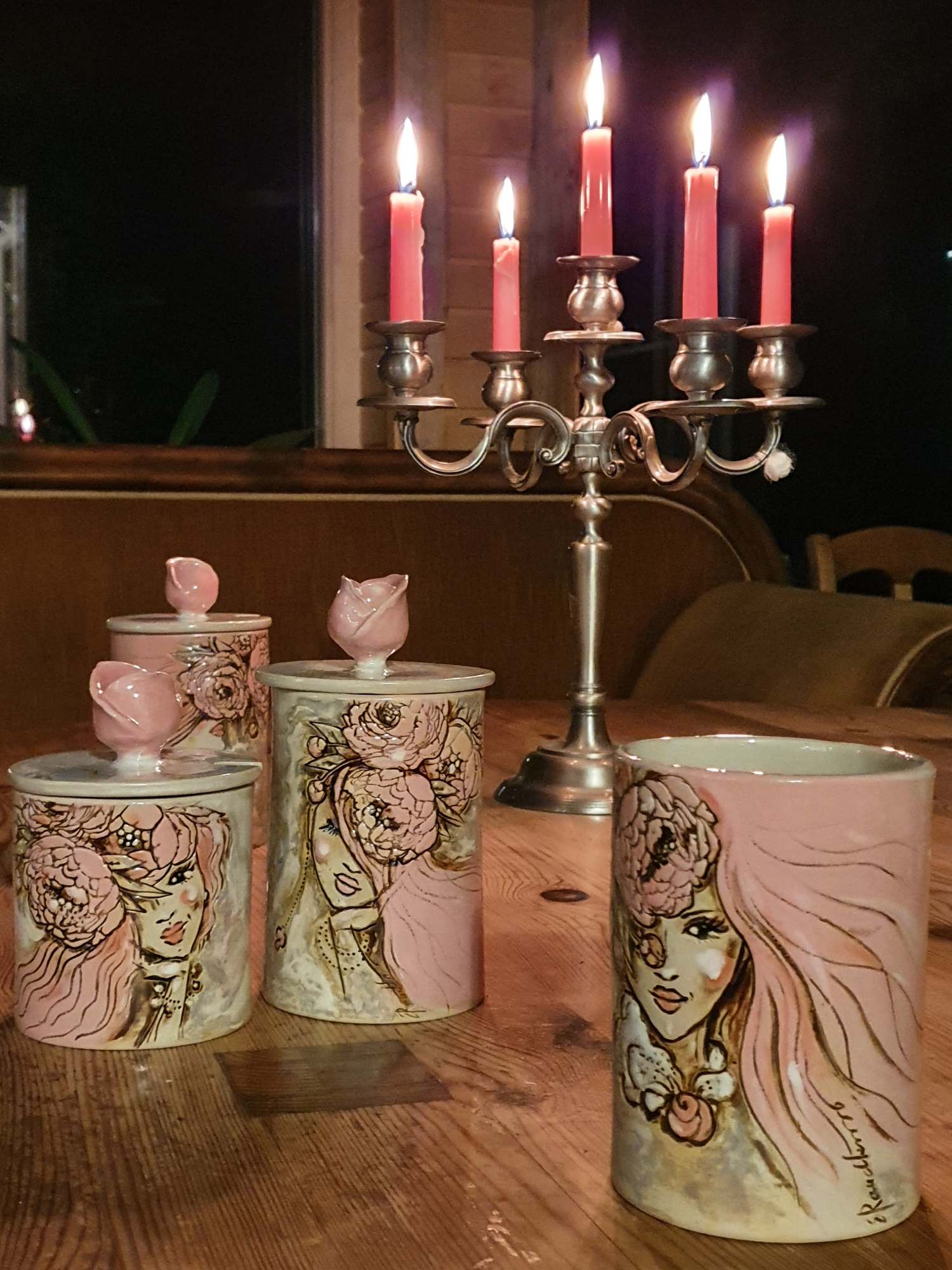 Hubane õhtune meeleolu põlevate küünaldega. Laual on kunstnik Eva Raudkivi signatuuriga keraamiline vaas ja kaks kaanega säilitustoosi kollektsioonist Pojengitar. Tooside kaasi kaunistavad ruumilised roosanupud.